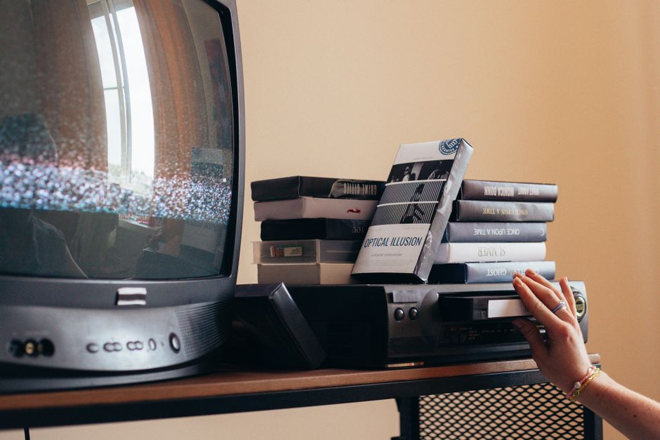 Person inserting a VHS tape into a vintage video cassette recorder (Image Credit: cottonbro studio - Pexels)