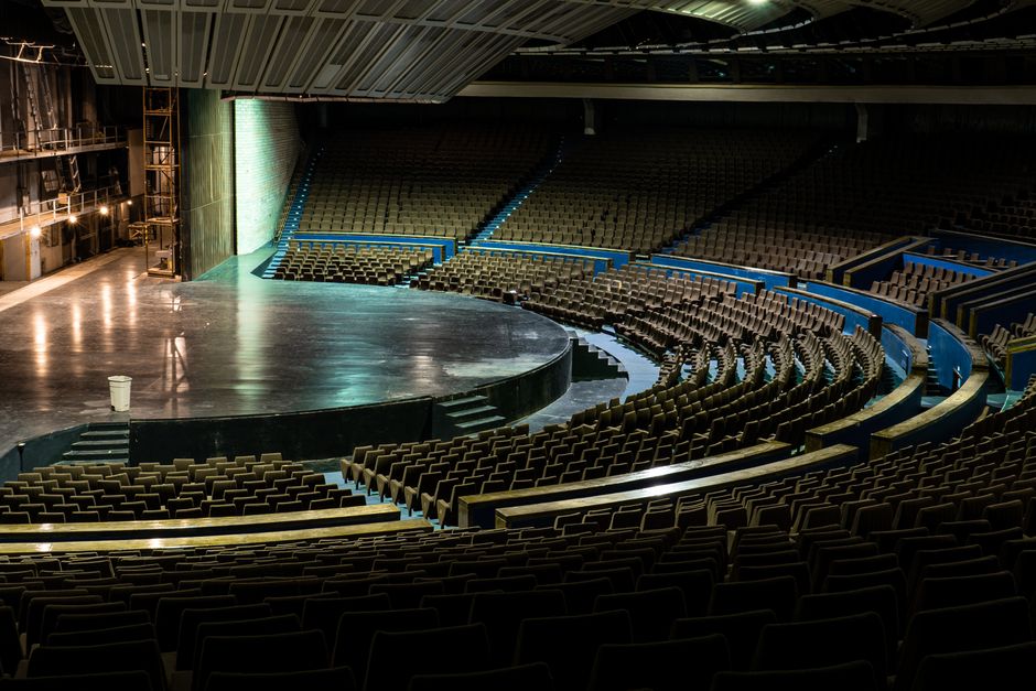 Empty circular auditorium with stage lighting and tiered seating (Image Credit: Alari Tammsalu - Pexels)
