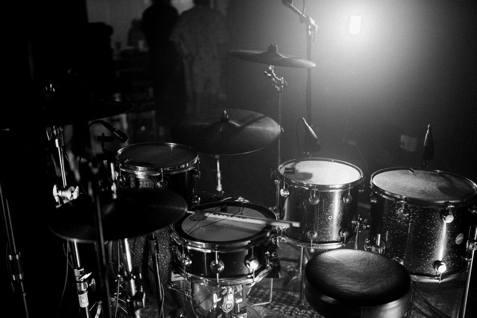 Black and white close-up of a snare drum and drum kit setup on stage (Image Credit: Hồ Thành - Pexels)