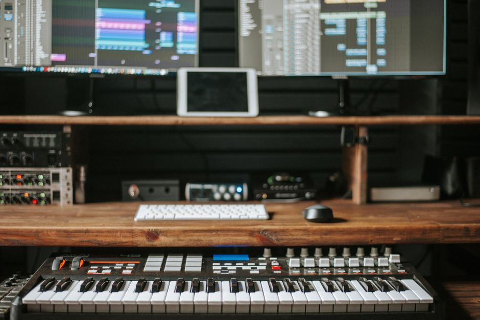 Modern digital audio workstation setup with computer monitors, keyboard, and speakers (Image Credit: John Taran - Pexels)