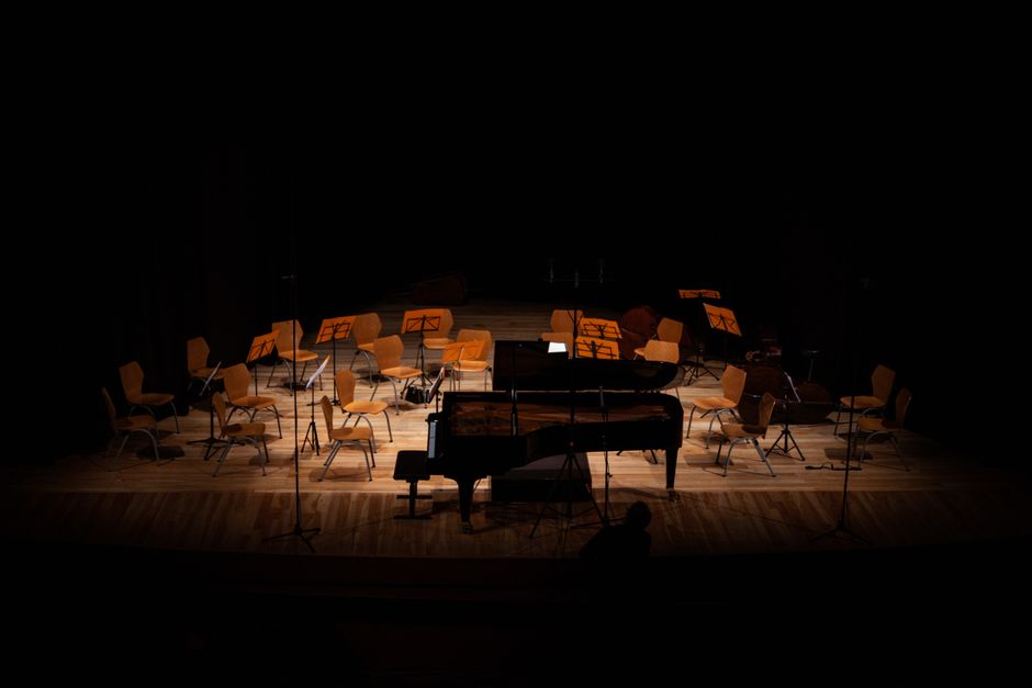 Grand piano on a dimly lit concert stage ready for orchestra (Image Credit: Matteo Basile - Pexels)