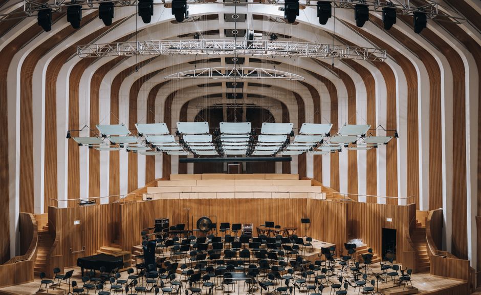 Spacious modern auditorium featuring warm wooden acoustic wall paneling (Image Credit: Masood Aslami - Pexels)