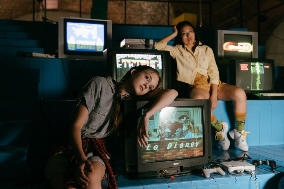 Two young women posing with vintage television sets and retro electronics (Image Credit: cottonbro studio - Pexels)