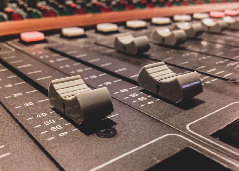 Studio audio engineer adjusting volume controls on a hardware mixing console (Image Credit: Donatello Trisolino - Pexels)