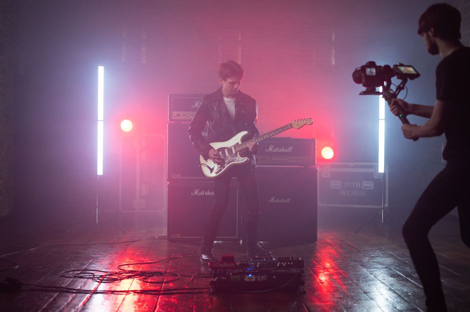 Guitarist performing on stage in a studio setting with vibrant lighting (Image Credit: Harry Shelton - Pexels)