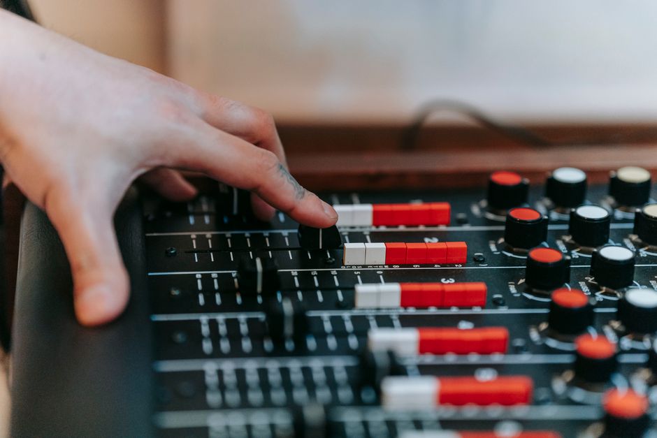 Hand adjusting faders on a modern digital audio console in a sound studio (Image Credit: Anna Pou - Pexels)