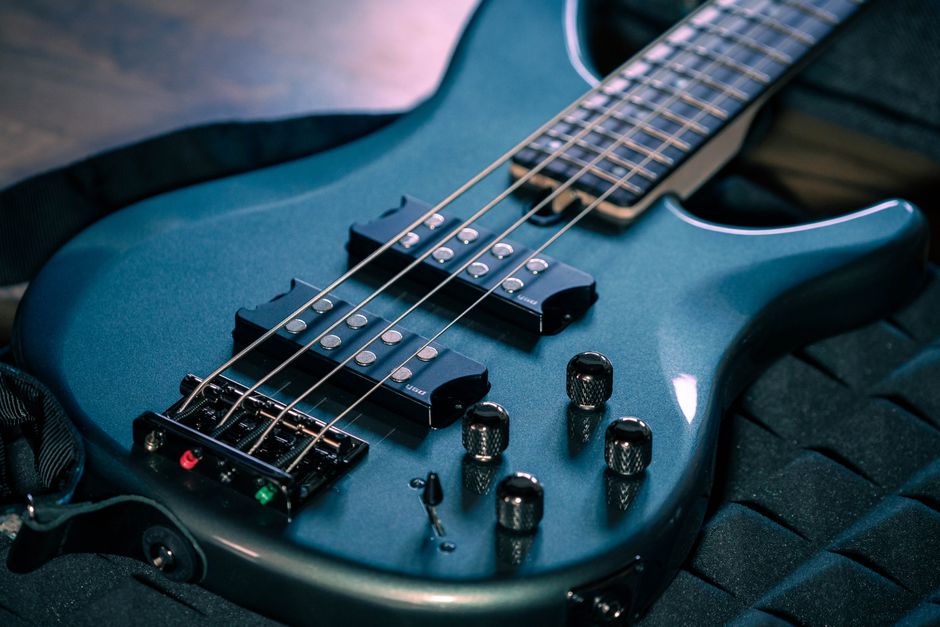 Detailed view of a dark blue electric bass guitar showcasing strings and controls (Image Credit: DiePhotoPotato - Pexels)